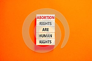 Abortion rights symbol. Concept words Abortion rights are human rights on wooden blocks. Beautiful orange background. Business