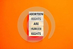 Abortion rights symbol. Concept words Abortion rights are human rights on wooden blocks. Beautiful orange background. Business