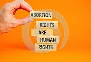 Abortion rights symbol. Concept words Abortion rights are human rights on wooden blocks Businessman hand. Beautiful orange table