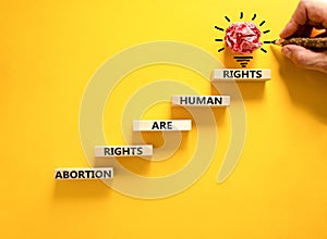 Abortion rights symbol. Concept words Abortion rights are human rights on wooden blocks. Businessman hand. Beautiful yellow