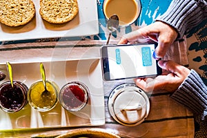 Above close up view of caucasian people use modern cellular phone internet and social media connected  during breakfast time at