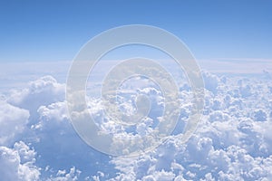 Above clouds. Aerial view from airplane window. Blue sky, many clouds background