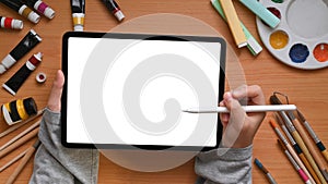 Above of creative designer hands is holding a white blank screen tablet