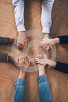Above, diversity or business people holding hands for support, team building or teamwork in office. Partnership, zoom or