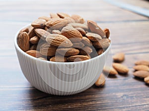 Above of dried almonds in bowl isolated on wooden table