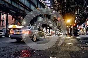 Above ground subway line and New York City street in Brooklyn with cars