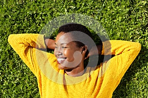 Above of happy young black woman lying on green grass