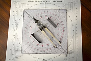 Above image of a navigator\'s radar plotting chart with a triangle and compass divider