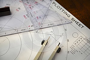 Above image of a navigator\'s radar plotting chart with a triangle and compass divider