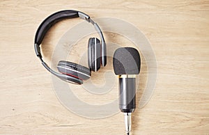 Above, microphone and headphones on a table for a podcast, radio or broadcast. Music, desk or musical gear, equipment or