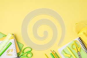 Above photo of pencil-case notebook pen pencil felt-tip scissors ruler and paperclips isolated on the yellow background with