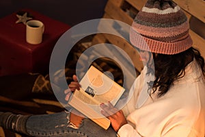 Above photography womanreading a book wears winter hat and white sweater on a cold night