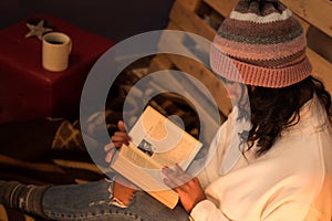Above photography womanreading a book wears winter hat and white sweater on a cold night photo