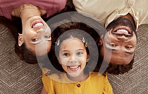 Above portrait of mixed race parents enjoying weekend with daughter in home living room. Smiling hispanic girl hugging