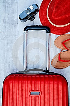 From above red suitcase beside flip-flop and retro camera on light background. Travel blogging or woman blogger or summer vacation