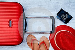 From above red suitcase beside flip-flop and retro camera on light background. Travel blogging or woman blogger or summer vacation