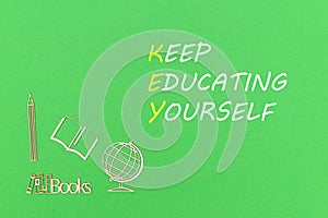 From above wooden minitures school supplies on green background with text keep educating yourself photo