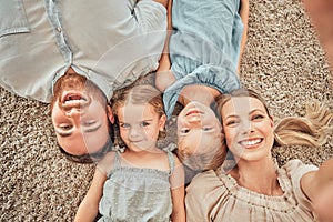 Above shot of a happy and loving family of four taking selfies while lying on their living room floor at home. A