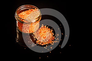 Above small glass jar with pile orange organic sea salt