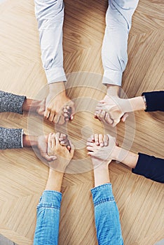 Above, solidarity or business people holding hands for support, team building or teamwork in office. Partnership, zoom
