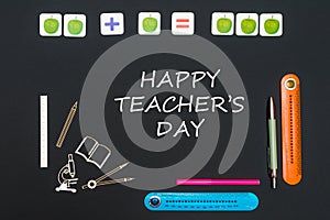 Above stationery supplies and text happy teacher`s day on black background