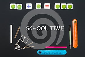 Above stationery supplies and text school time on blackboard