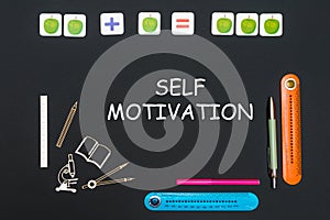 Above stationery supplies and text self motivation on blackboard