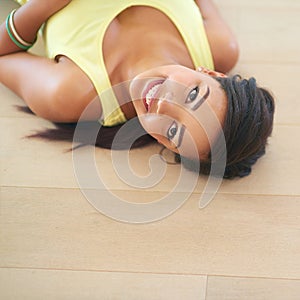 Above, teenage girl and lying on floor with smile for holiday break and relax with playful attitude indoor. Young person
