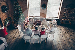 Above top high angle view of noel evening family gathering in loft living room. Grey-haired grandparents, brother boy