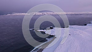 Above view of Barents sea and snowy coast in winter during sunset