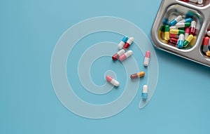 Above view of Colorful antibiotic capsule pills on a tray and blue background. Antibiotic drug resistance. Antimicrobial drugs.