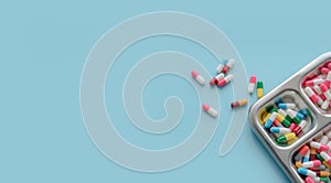 Above view of Colorful antibiotic capsule pills on a tray and blue background. Antibiotic drug resistance. Antimicrobial drugs.