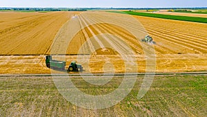 Above view on combine, tractor waits for transshipment as harvester harvest wheat