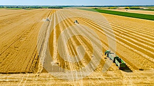 Above view on combine, tractor waits for transshipment as harvester harvest wheat