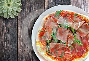 Above view of fresh homemade delicious italian pizza with Serrano ham and arugula