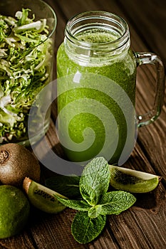 From above view of green smoothie with fruits and greenery on wood rustic table. selective focus
