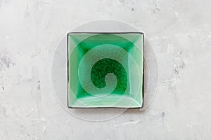 Above view of green square saucer on gray concrete