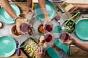 Above view of group of friends people eat and drink together celebrating and having fun toasting with red wine - coloured table