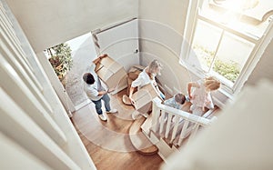 Above view happy caucasian family moving into their new home and carrying boxes up a staircase. Parents and kids moving