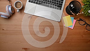 Laptop, sticky note, headphone and coffee cup on wooden table.