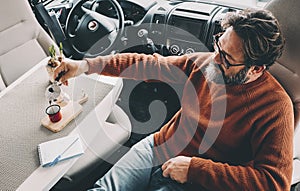 Above view of a man alone drinking italian moka traditional coffee inside his camper van travel home alternative vehicle.