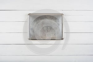 Above View of a Metal Cookie Sheet Cooking Pan Laying or Hung in center of a Rustic White or Gray Wood Board Background blank area