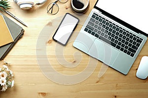 Above view mock up laptop computer, smart phone, coffee cup and notebook on wooden table