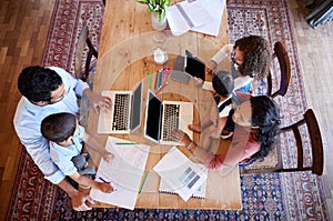 Above view parents working from home with kids. Couple working on laptops at table with daughters and son. Family