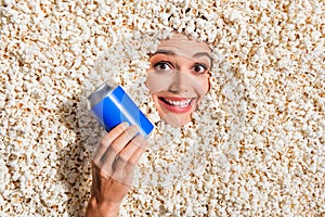 Above view photo of cheerful funky lady toothy smile hold cola pepsi soda drink can face buried isolated in pop corn