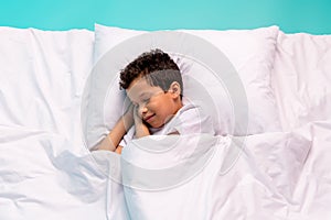 Above view portrait of peaceful schoolkid laying sleeping comfy bed sheets pillow covered blanket isolated on turquoise