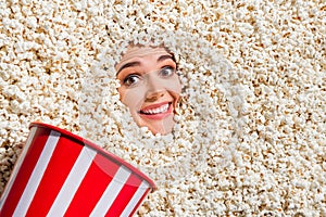 Above view portrait of positive crazy person toothy smile big bucket face buried isolated in popcorn background