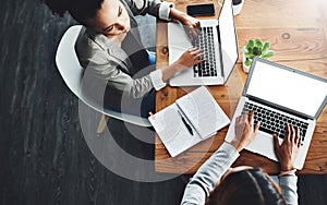 Above view of professional employees talking and working together on a strategy project on their laptop in a modern