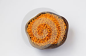 Raw, Dry Red Lentil Heap in a wooden bowl on white surface with copy space