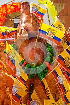 Above view of roaste pig body with ecuadorian flags around the body and gorgeous peppers around the neck - Ecuadorian photo